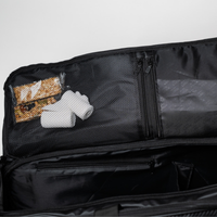 Offener Koffer mit Netztasche, die Socken und zwei Müsliriegel enthält, mit leeren Fächern darunter.