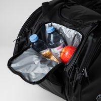 Eine schwarze Sporttasche mit einer offenen Tasche für zwei Wasserflaschen, einen roten Apfel und einen Müsliriegel.