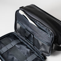 Offener schwarzer Kulturbeutel mit einer Zahnbürste, Netztaschen und elastischen Riemen im Inneren.